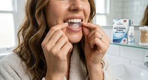 A person applying UK-compliant whitening strips to their teeth to remove coffee stains as part of a home dental routine.