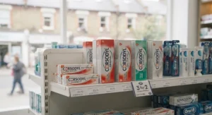Corsodyl toothpaste displayed on a shelf in a typical British high street chemist like Boots or Superdrug.