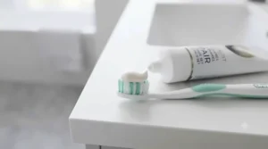 A pea-sized amount of fluoride toothpaste formulated for gum recession squeezed onto soft toothbrush bristles.