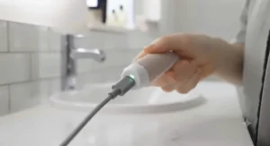 USB charging cable plugged into a portable electric gum massager, highlighting long battery life for home use.