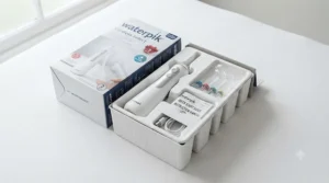 Unboxed Waterpik gum stimulator showing the ergonomic handle, charging cable, and interchangeable accessory tips.